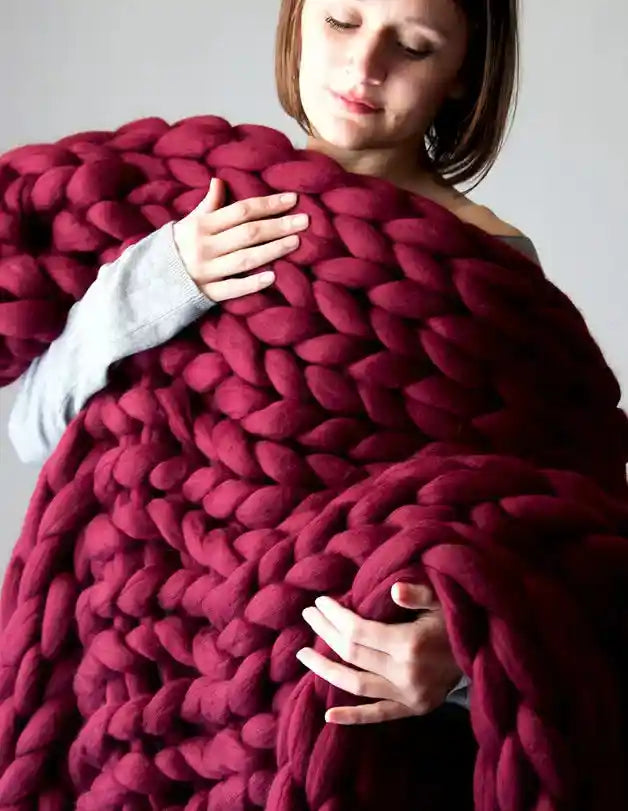 Burgundy chunky knit blanket held by person